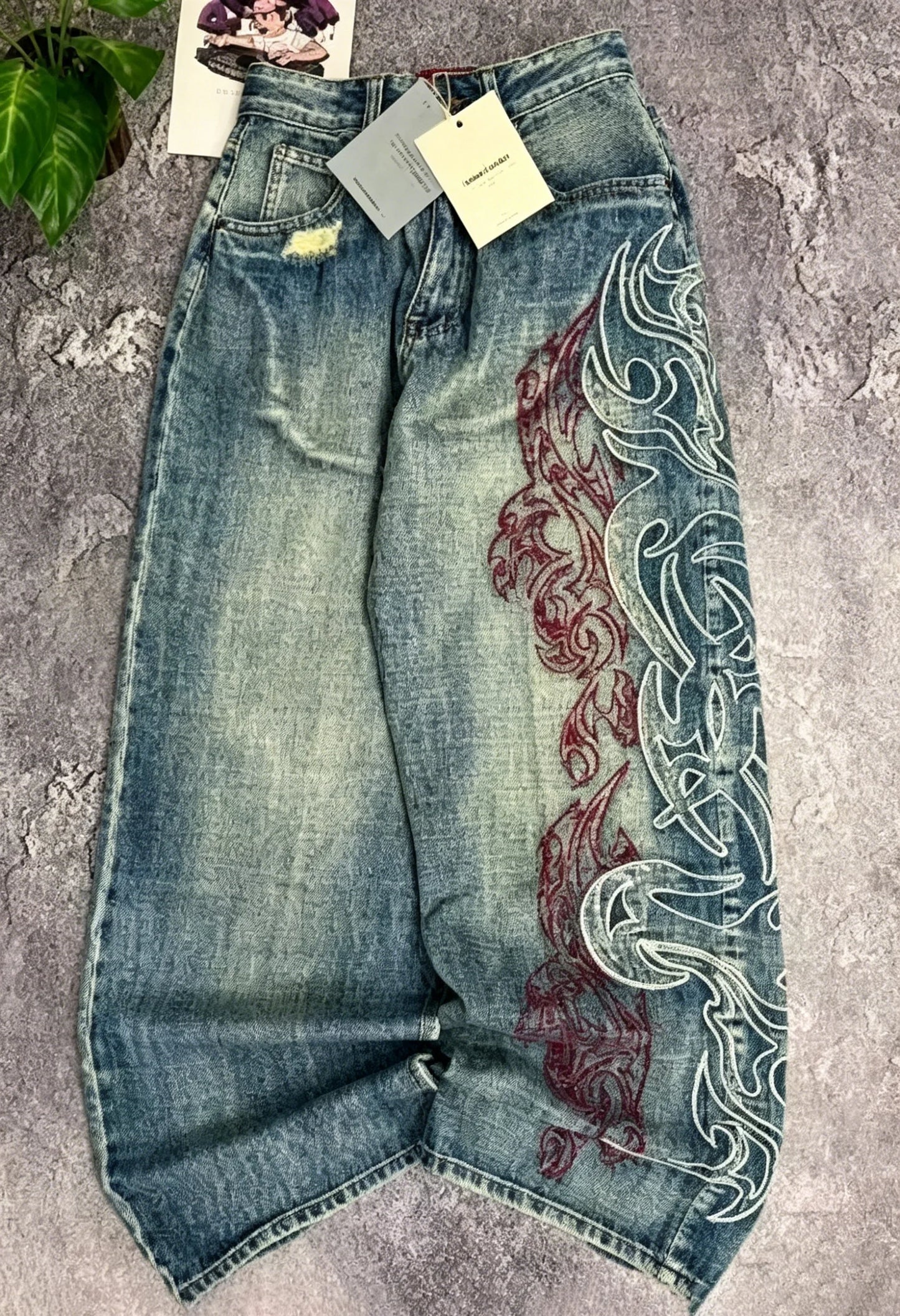Vintage-style high-waisted wide-leg jeans with side print, distressed finish, loose straight leg, casual and stylish.